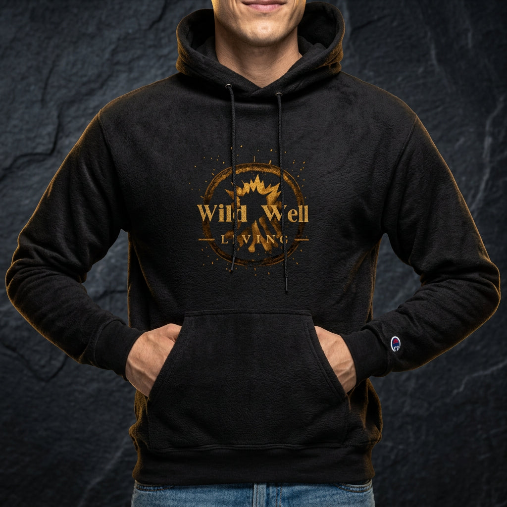 Wild Well Living black hoodie with gold emblem on dark stone backdrop